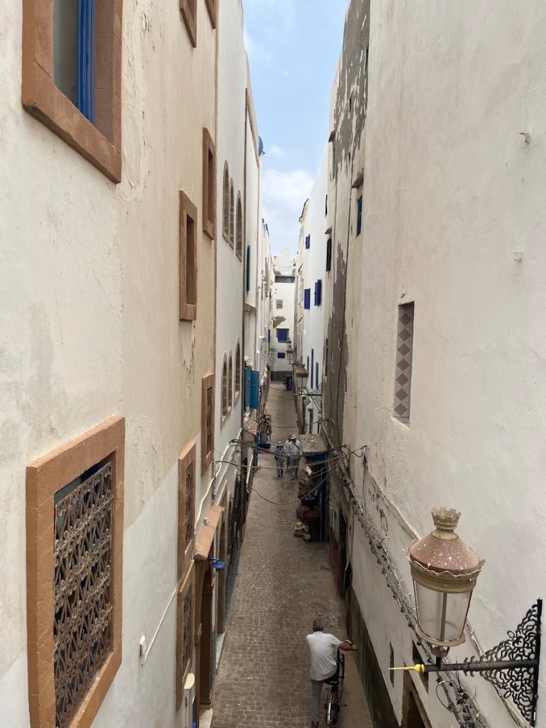 Charming alleyway in Essaouira, Morocco, showcasing historic white and blue architecture.